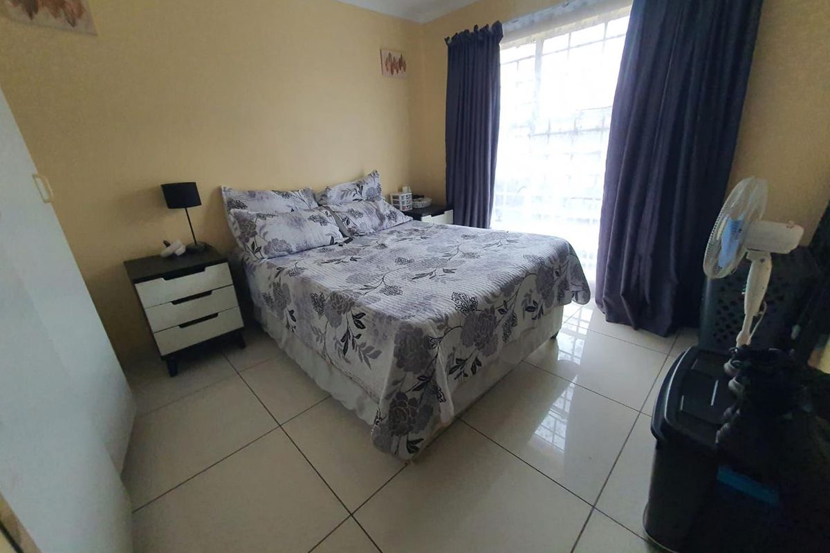 A bedroom featuring large format floor tiles and a window with curtain tracks, providing a functional and well-lit sleeping space.