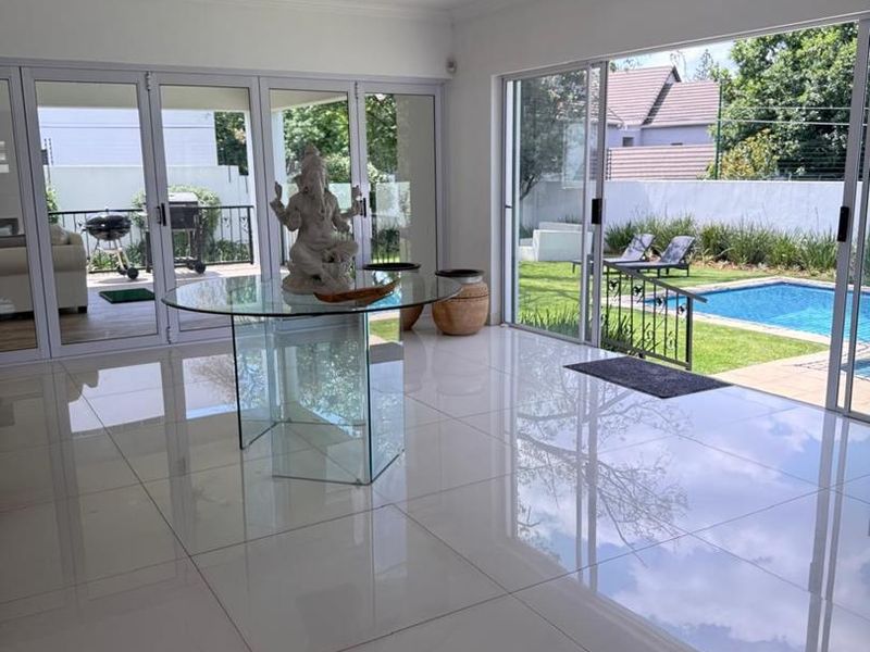 Bright living area featuring large format porcelain tiles, recessed lighting, and expansive glass doors providing seamless indoor-outdoor flow to the pool and garden.