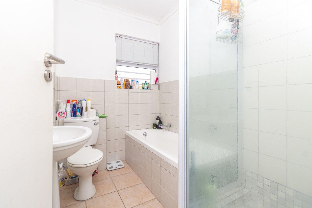 A functional bathroom featuring a pedestal basin, toilet, bathtub, and a separate shower enclosure with tiled finishes throughout.