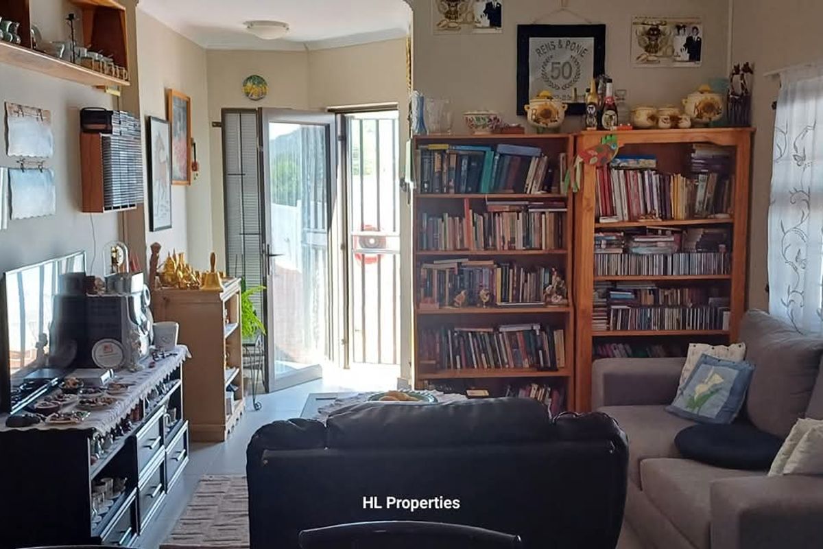 A living room area featuring tiled flooring, a security gate at the entrance, and large windows allowing natural light into the space.