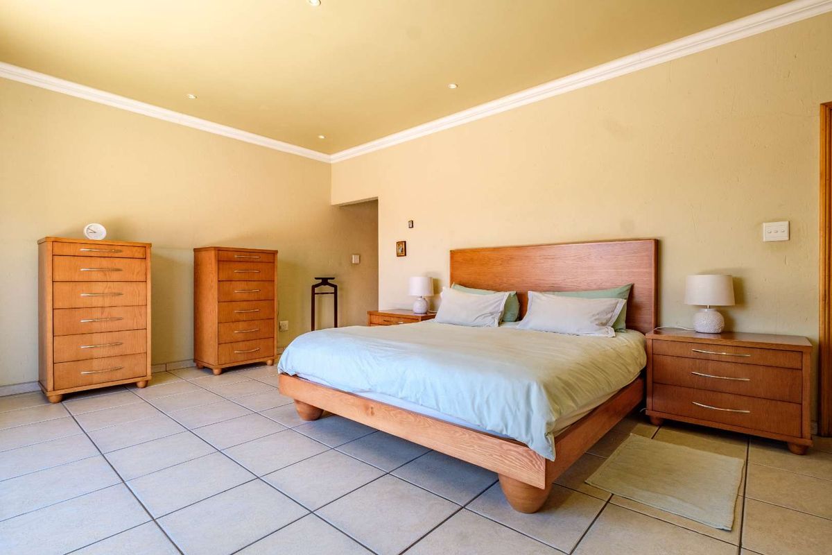 Spacious bedroom featuring neutral wall tones, tiled flooring, and crown molding, providing a comfortable and functional sleeping area.