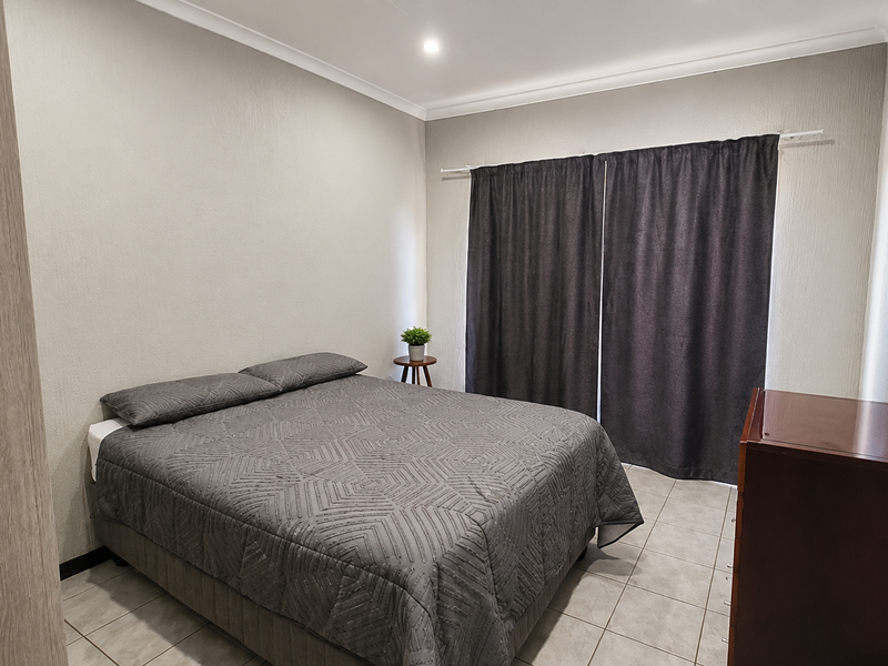 A well-maintained bedroom featuring neutral wall finishes, tiled flooring, and built-in storage, providing a clean and functional living space.