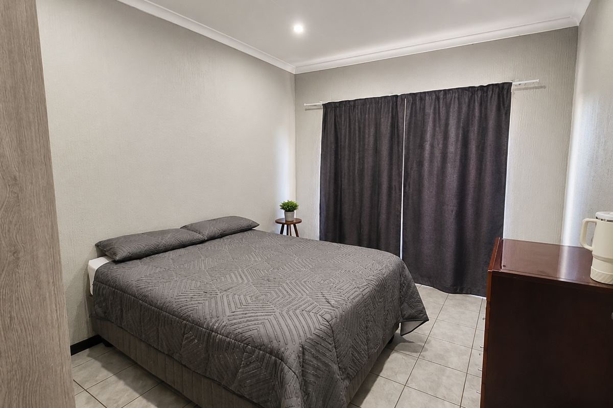 A well-maintained bedroom featuring neutral wall finishes, tiled flooring, and built-in storage, providing a clean and functional living space.