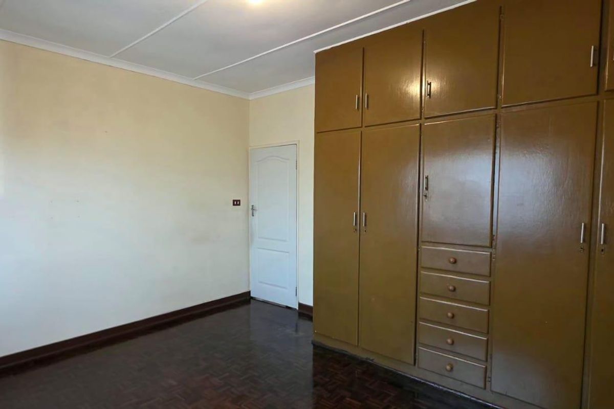 A vacant bedroom featuring original parquet flooring, coved ceilings, and extensive built-in wooden cabinetry providing ample storage space.