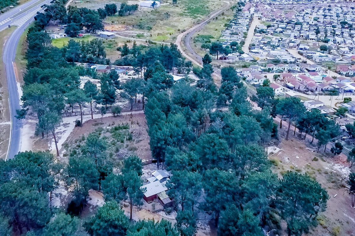 Aerial view of the small holding property, showcasing the surrounding landscape, mature trees, and proximity to local infrastructure and residential areas.