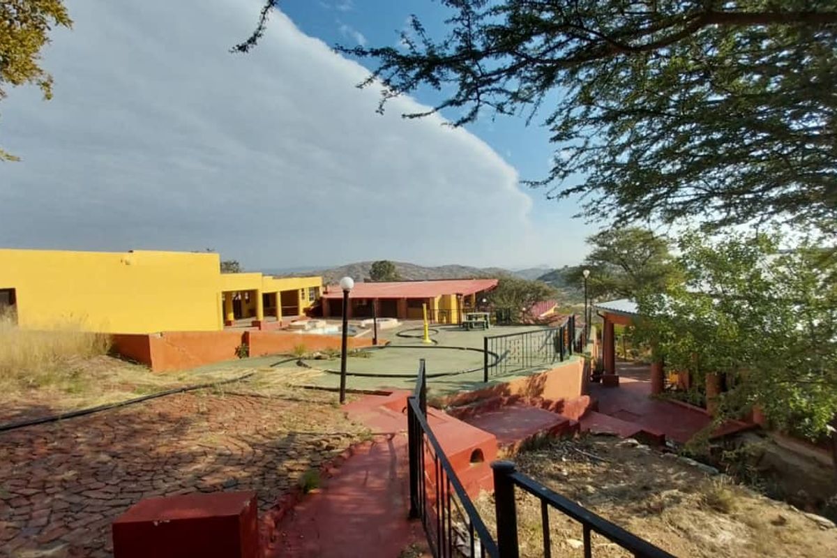 An elevated view of the property exterior featuring tiered paved pathways, outdoor entertainment areas, and surrounding landscape views.