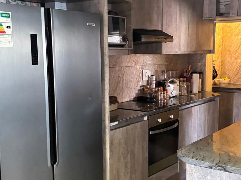Modern kitchen featuring wood-look cabinetry, stone countertops, built-in oven, extractor fan, and a timber ceiling, offering a contemporary and functional cooking space.