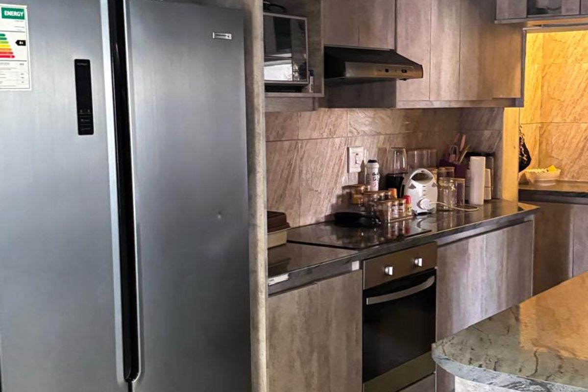 Modern kitchen featuring wood-look cabinetry, stone countertops, built-in oven, extractor fan, and a timber ceiling, offering a contemporary and functional cooking space.