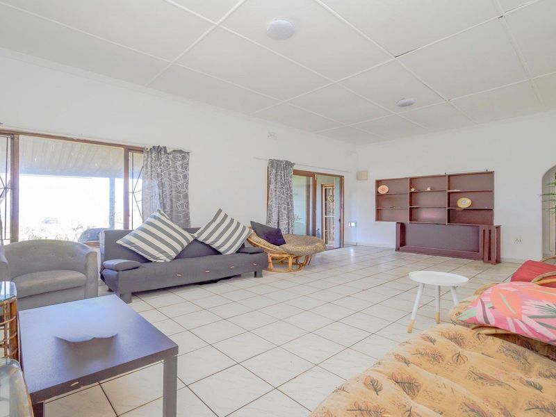 Spacious living room featuring tiled flooring, a built-in shelving unit, and sliding glass doors providing access to the outdoor area.