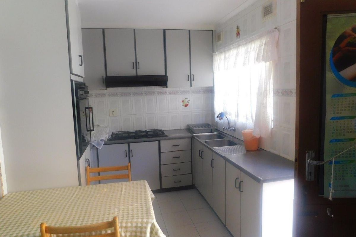 A functional kitchen featuring built-in cabinetry, a gas hob, an integrated oven, and a double sink with tiled splashbacks and flooring.