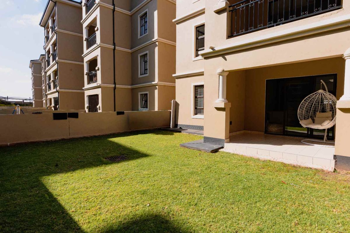 A ground floor apartment featuring a private tiled patio area and a well-maintained lawn, providing direct outdoor access from the living space.