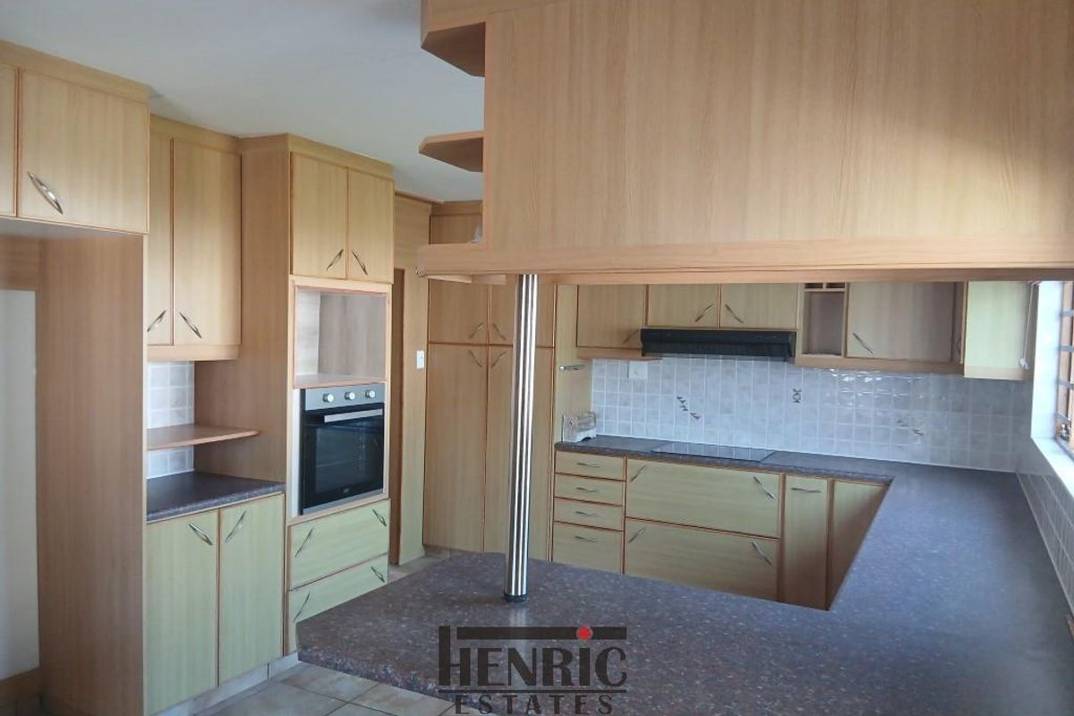 A functional kitchen featuring light wood-look cabinetry, built-in oven, extractor fan, and a breakfast bar with ample counter space.