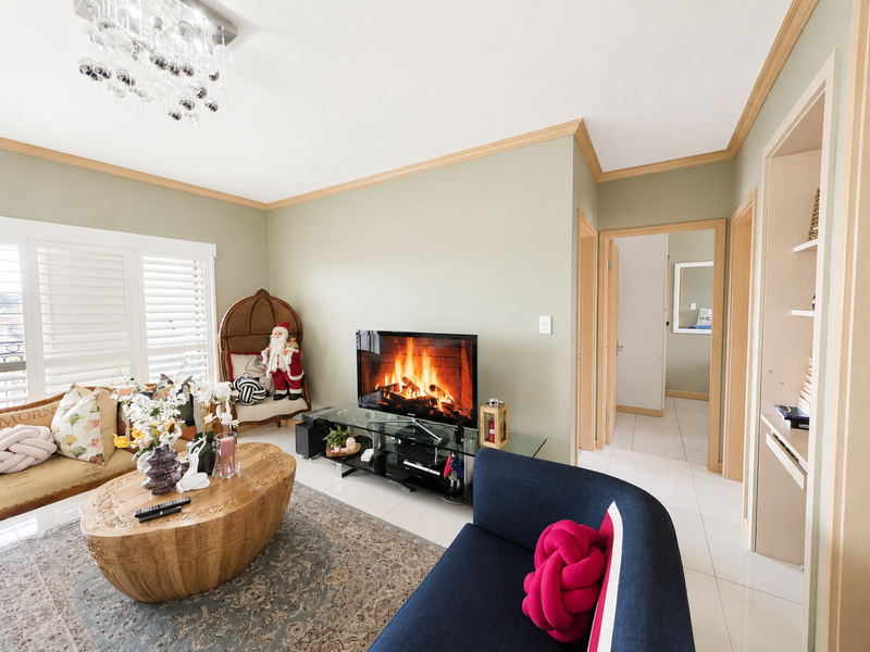 A well-maintained living room featuring crown molding, tiled flooring, and built-in shelving, offering a comfortable and inviting atmosphere.