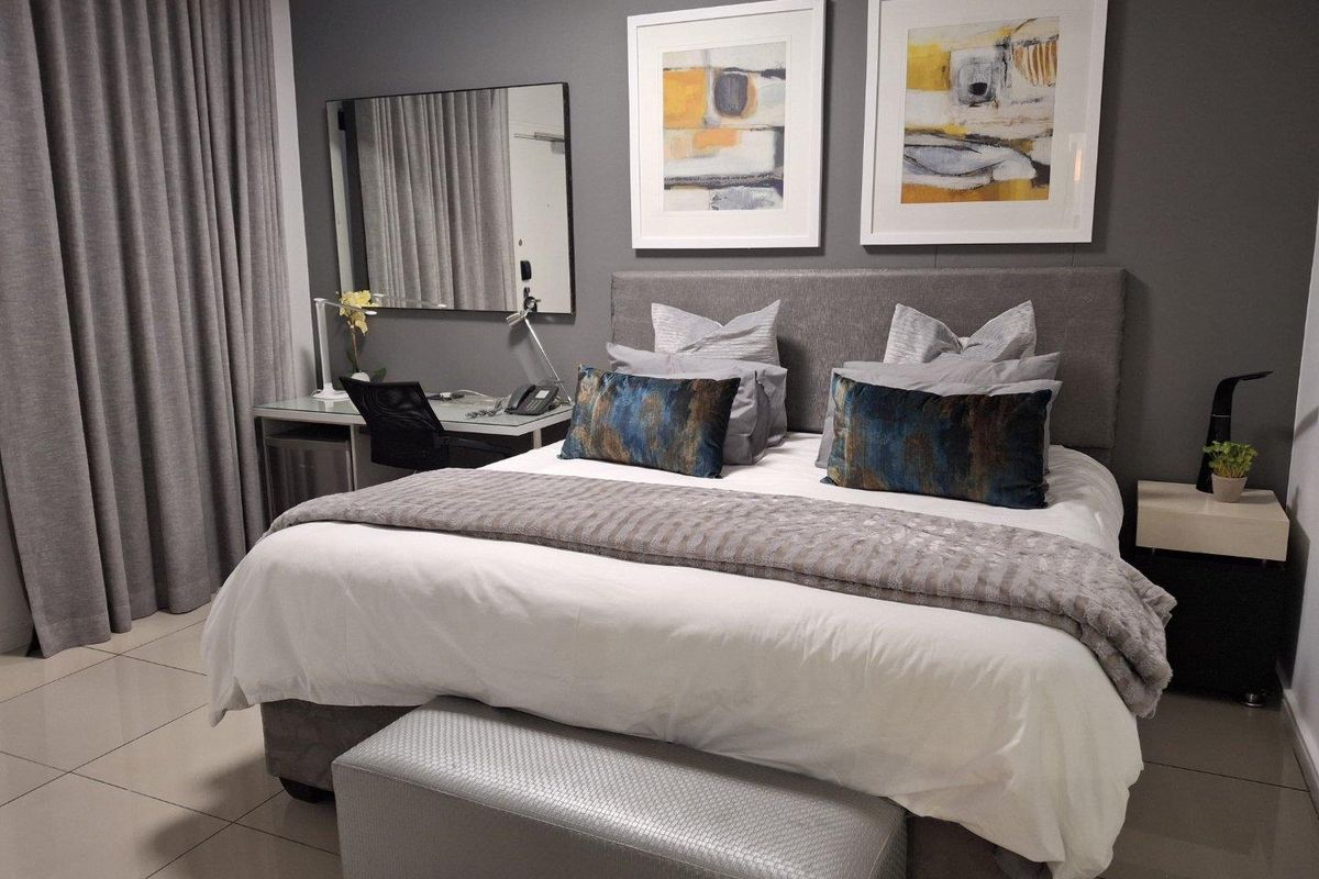 A well-maintained bedroom featuring neutral tiled flooring and modern grey wall finishes, creating a comfortable and contemporary living space.