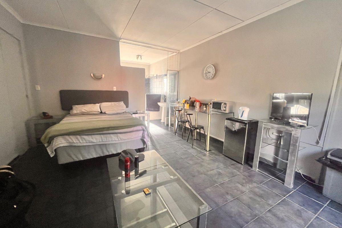 A studio-style bedroom featuring tiled flooring, a drop ceiling, and direct access to an en-suite bathroom area.