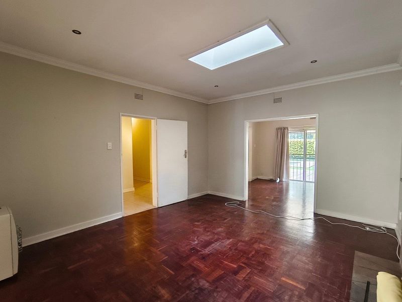 Spacious living area featuring classic parquet flooring, a central skylight for natural illumination, and coved cornicing, offering a versatile blank canvas.