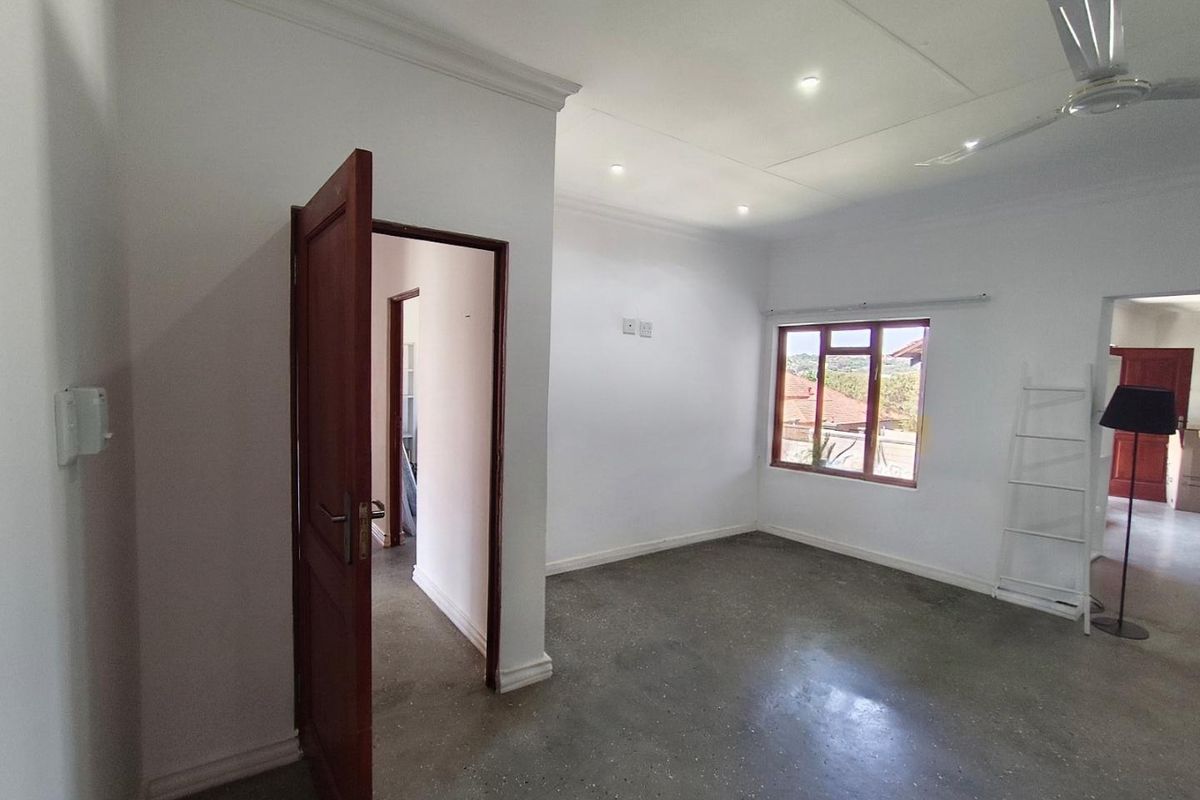 A bright, empty bedroom featuring polished concrete floors, recessed ceiling lighting, a ceiling fan, and timber-framed windows.