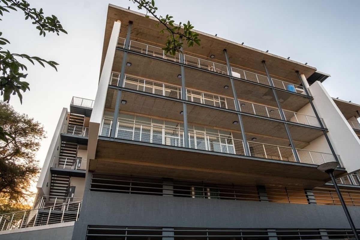 Modern multi-story office building featuring exposed concrete balconies, steel railings, and an external staircase, showcasing contemporary architectural design.