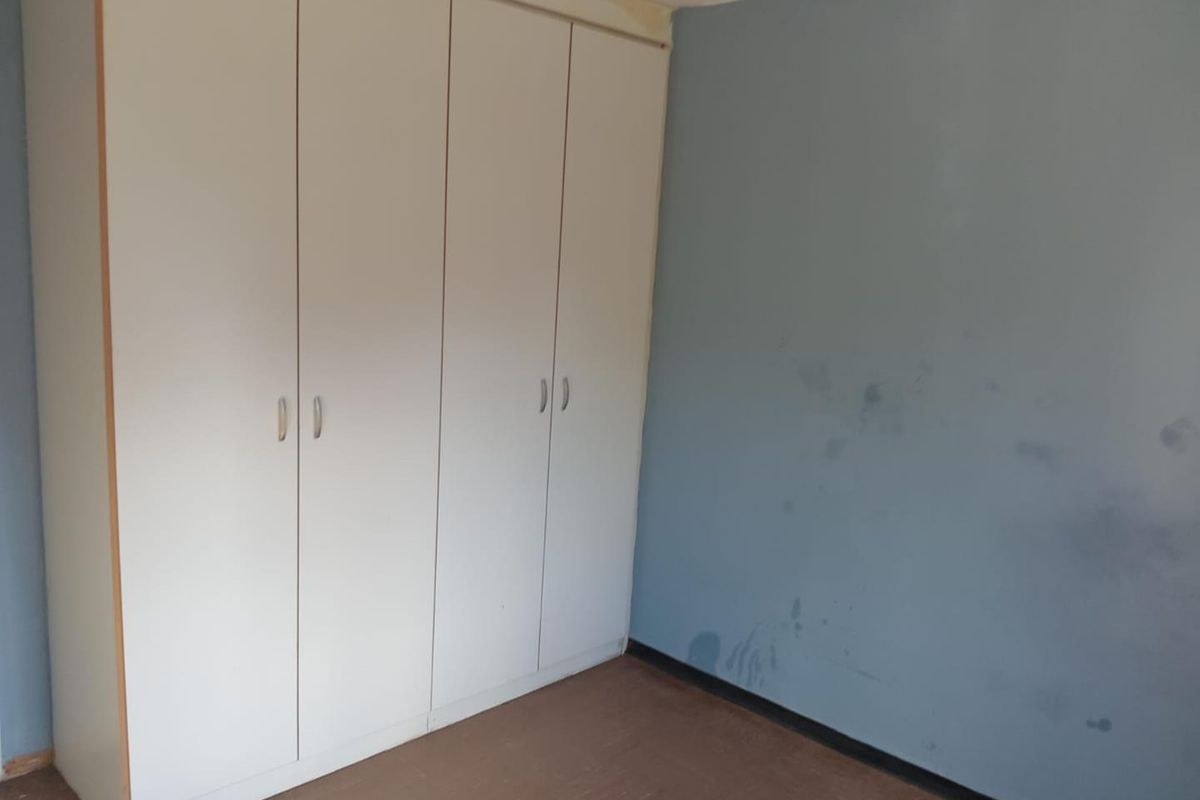 A bedroom featuring built-in cupboards, requiring cosmetic updates to the walls and flooring to improve its overall condition.