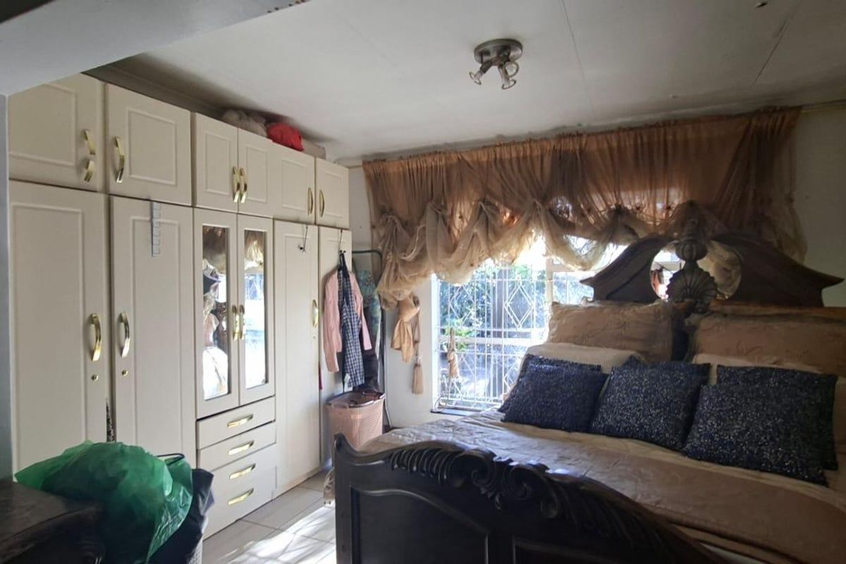 A bedroom featuring built-in cabinetry and security bars on the window, requiring cosmetic updates to modernize the space.