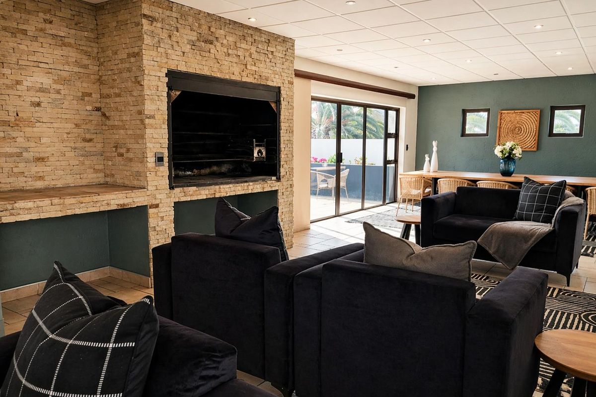 Spacious living area featuring a prominent stone-clad built-in fireplace, tiled flooring, and large sliding glass doors providing access to the outdoor patio.