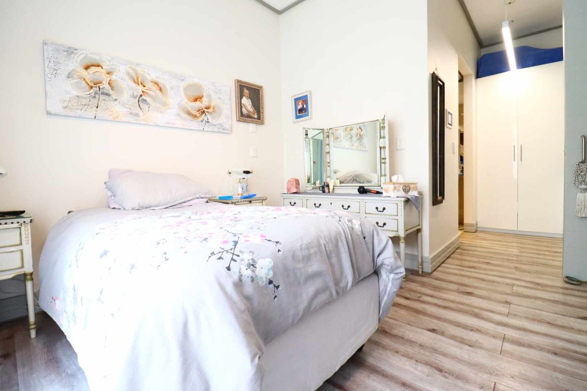 A well-maintained bedroom featuring light-toned laminate flooring, neutral walls, and built-in storage cupboards.