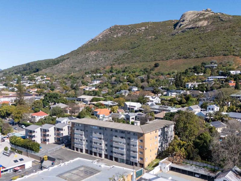 Aerial view of a multi-story apartment building situated in a residential neighborhood with mountain views.