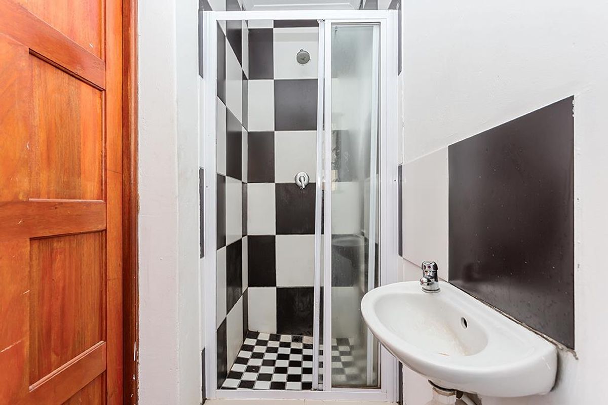 A compact bathroom featuring a shower enclosure with black and white checkered tiling and a wall-mounted basin.