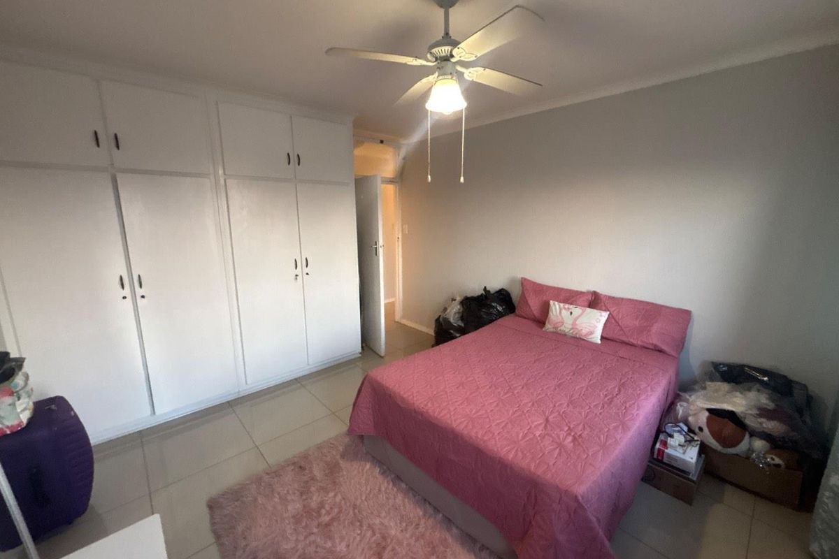 A bedroom featuring built-in cupboards, a ceiling fan, and tiled flooring.