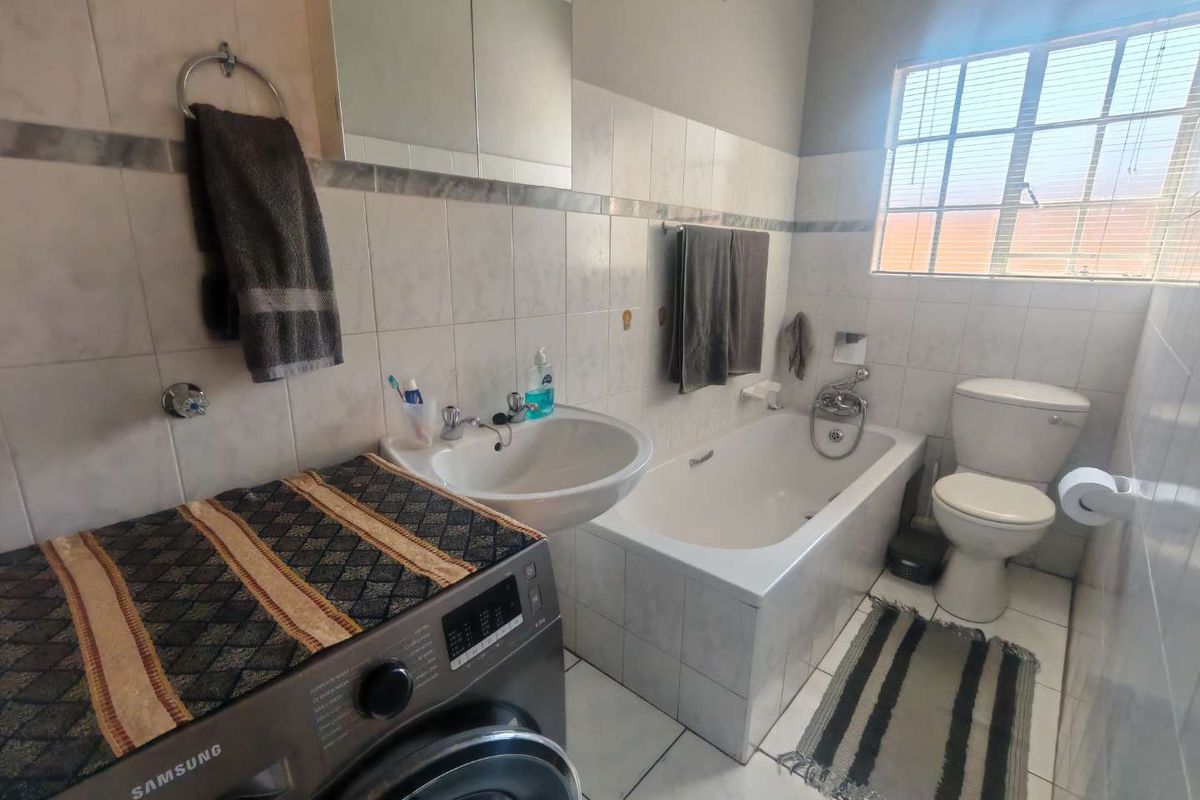 A functional bathroom featuring a built-in bathtub, pedestal washbasin, toilet, and tiled finishes, providing a practical layout for daily use.