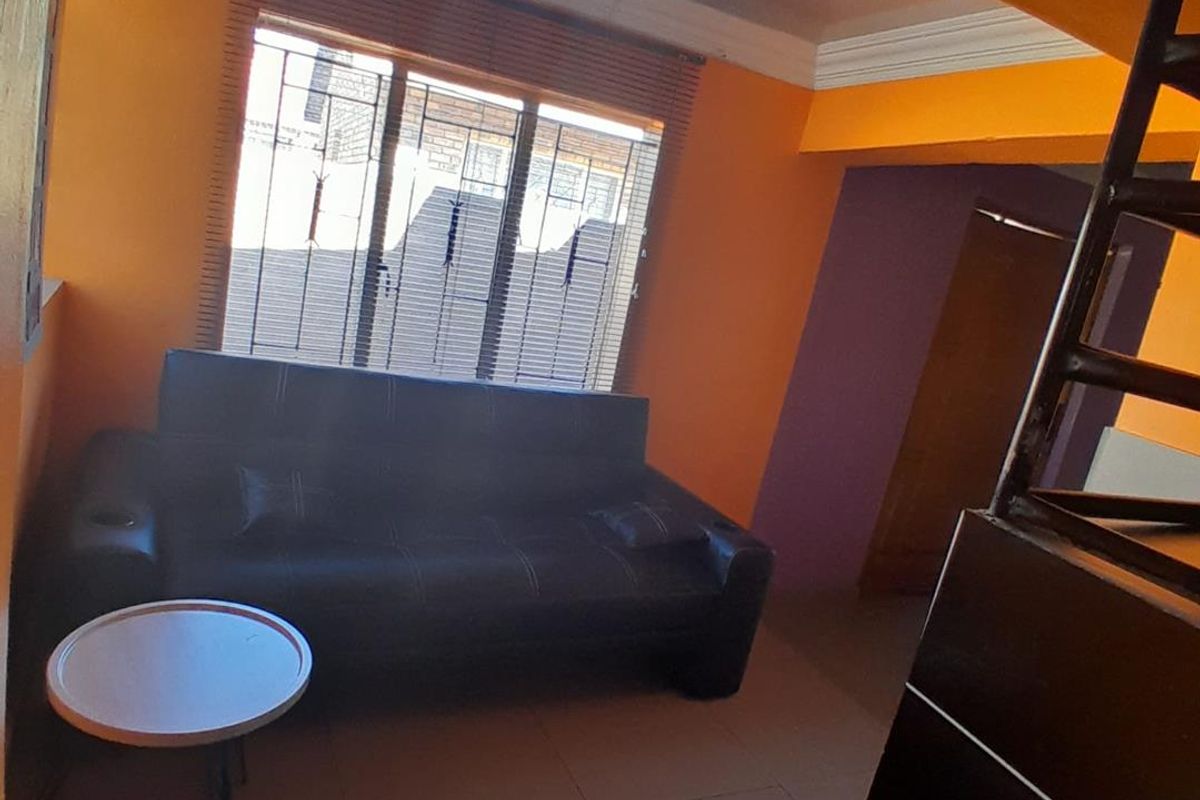 A living area featuring tiled flooring, decorative cornice, and venetian blinds, currently finished with bold orange wall paint.
