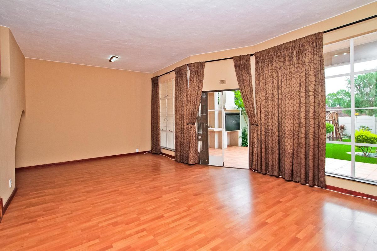 Spacious, empty living room featuring laminate flooring, large windows, and direct access to an outdoor patio area.
