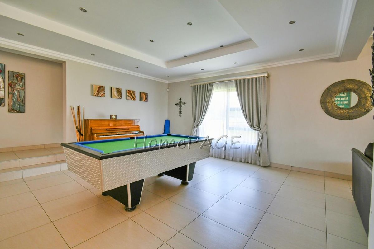 Spacious living area featuring tiled flooring, recessed ceiling lighting, and a raised platform area, suitable for a games room or lounge.