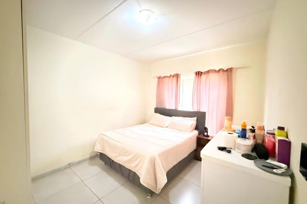 A standard bedroom featuring tiled flooring and a window with curtain tracks.