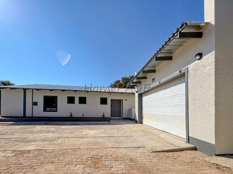 Front exterior view of the property featuring a paved driveway, a single garage with a sectional door, and a well-maintained stucco facade.