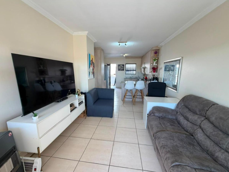 Open plan living and kitchen area featuring tiled flooring, neutral walls, and a functional kitchen layout with a central island.