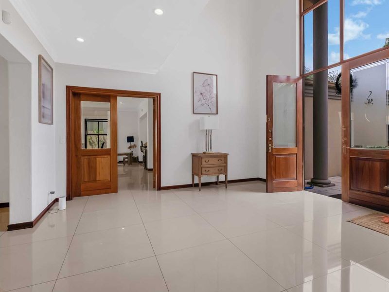 Spacious entrance hall featuring high ceilings, large format floor tiles, and elegant timber-framed doors leading to adjacent living areas.