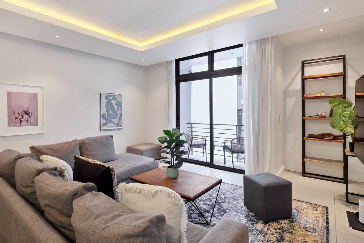 Modern living room featuring recessed cove lighting, tiled floors, and large sliding glass doors providing access to a private balcony.
