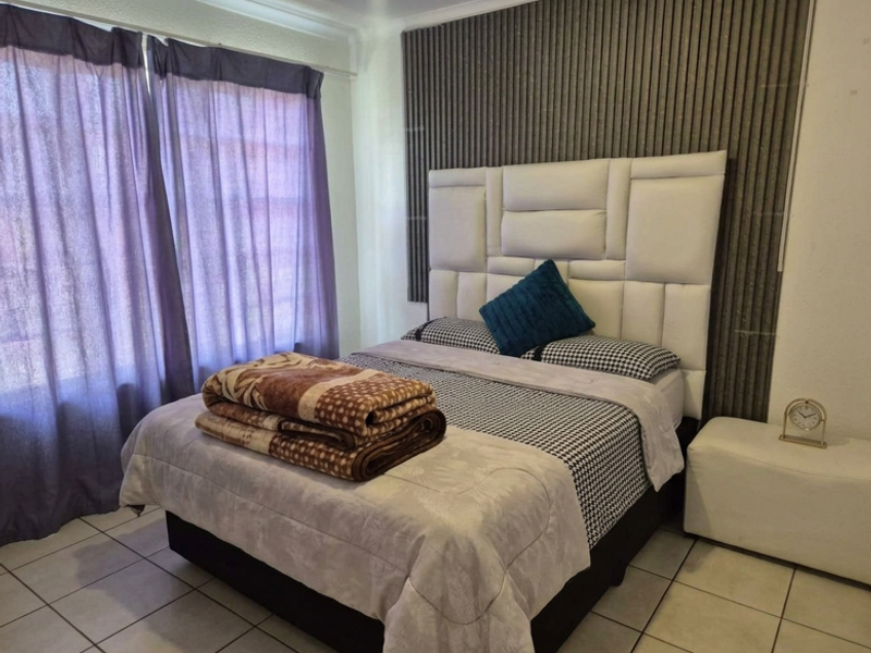A bedroom featuring tiled flooring and a decorative slatted wall panel behind the bed area.
