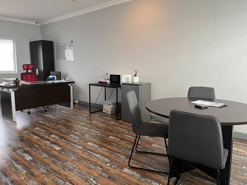 A functional office space featuring durable laminate wood flooring and a neutral wall finish, suitable for professional use.