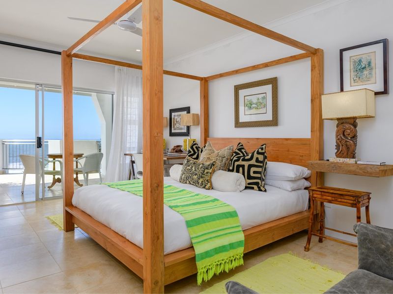 Spacious bedroom featuring tiled flooring, recessed lighting, a ceiling fan, and direct access to a private balcony with ocean views.