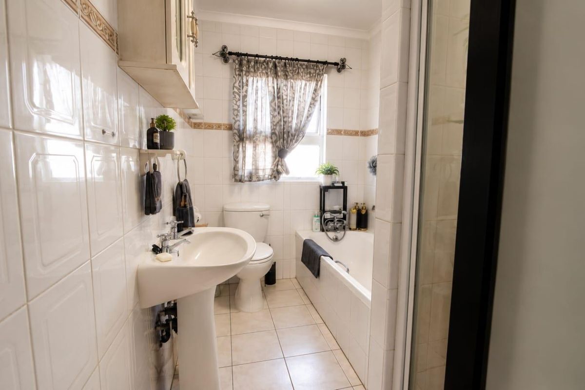 A functional bathroom featuring a pedestal basin, toilet, built-in bathtub, and a separate shower enclosure with classic white wall tiling.