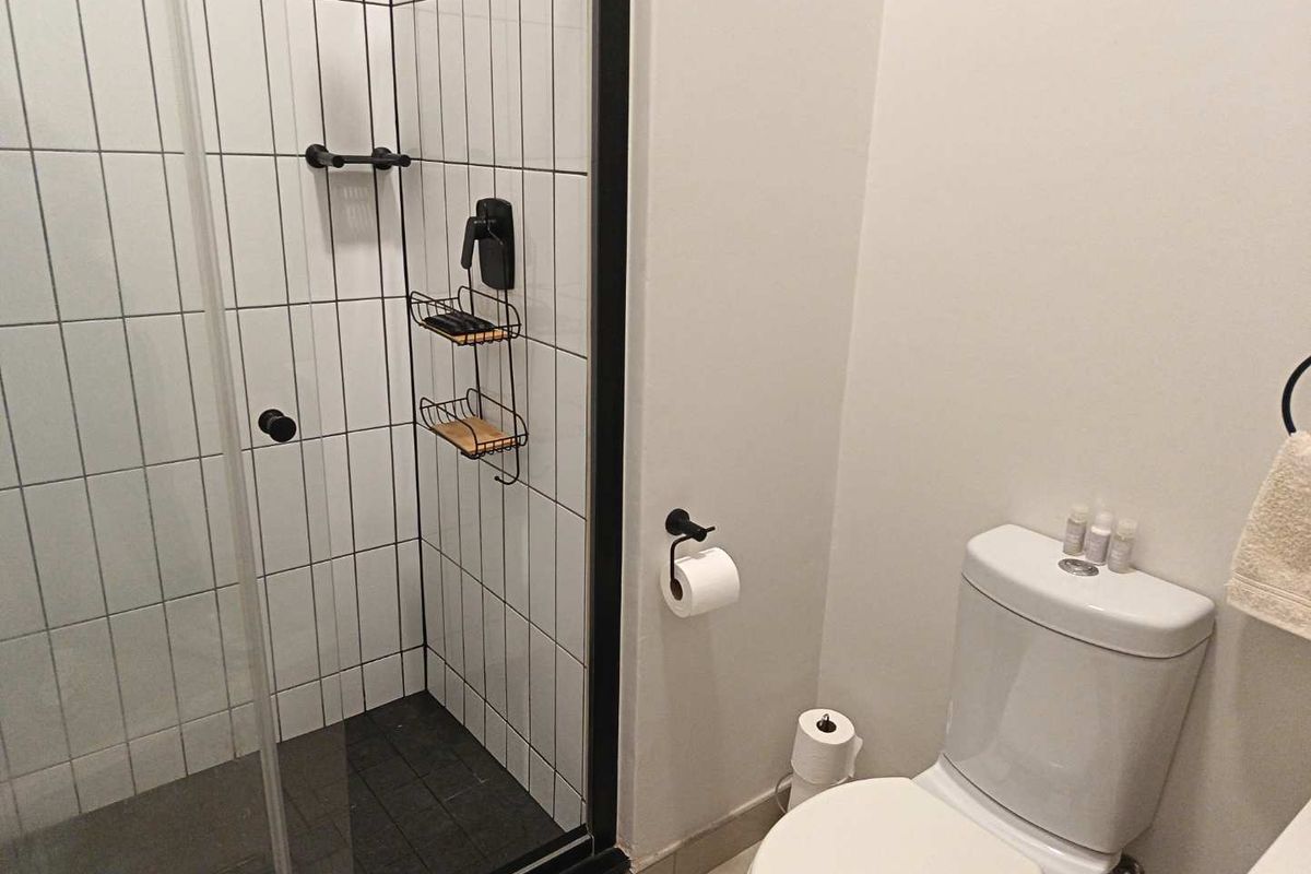 Modern bathroom featuring a glass-enclosed shower with vertical white tiling and a contemporary toilet suite with matte black fixtures.