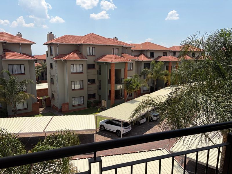 View of the apartment complex exterior featuring multi-story residential blocks, tiled roofing, and covered parking facilities within a landscaped estate setting.