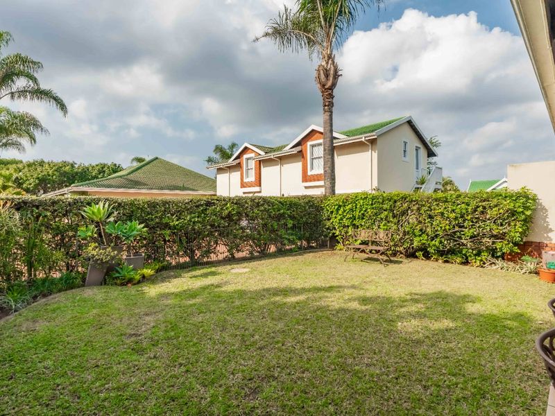 A well-maintained private garden featuring a manicured lawn and established hedge boundary, providing a pleasant outdoor space for the townhouse.