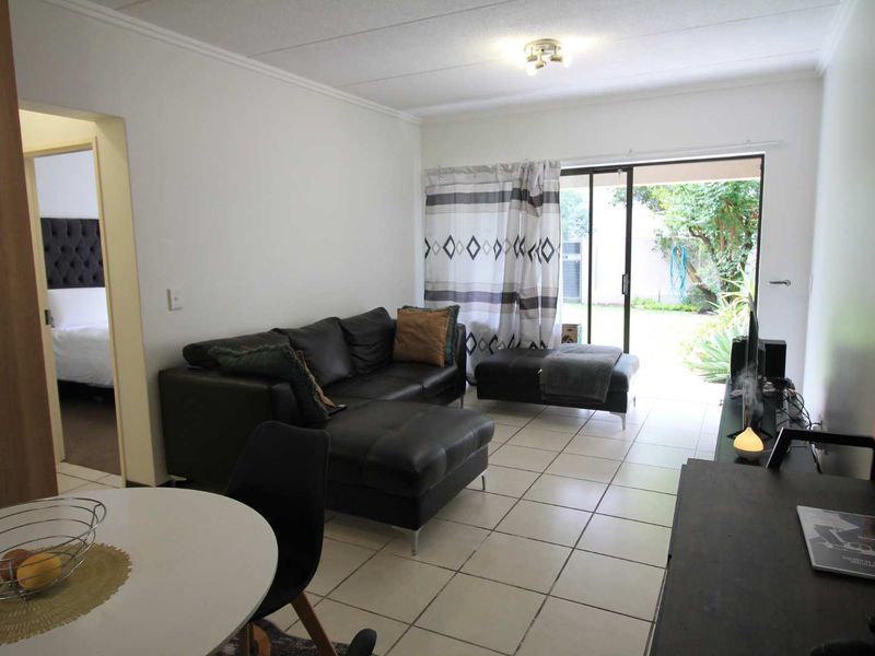 Open plan living area featuring tiled flooring and a sliding glass door providing direct access to the garden.