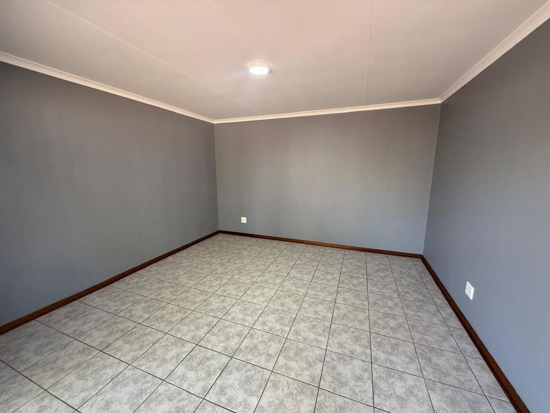 A clean, empty bedroom featuring neutral grey walls, tiled flooring, and coved cornicing, providing a versatile blank canvas for interior design.