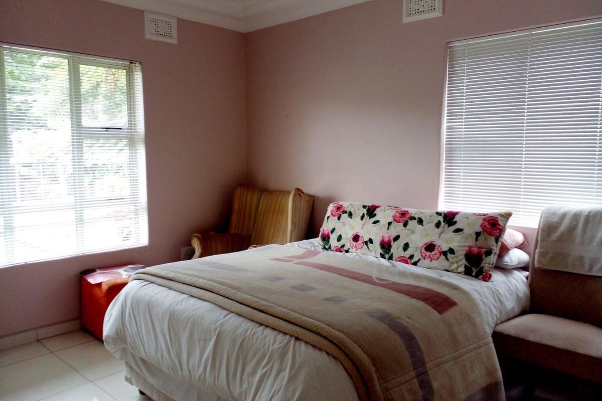 A bedroom featuring tiled flooring, dual windows with venetian blinds, and decorative ceiling cornicing.