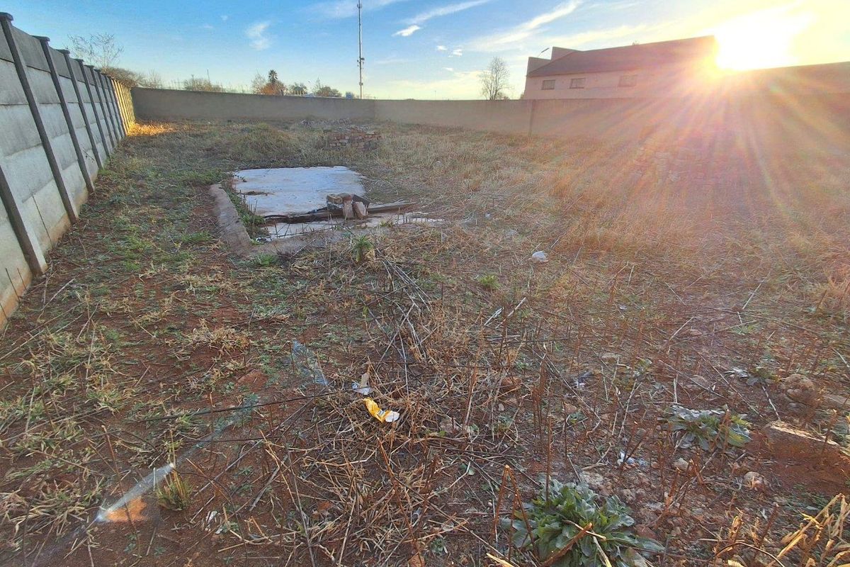 An undeveloped plot of land featuring a precast concrete boundary wall and an existing concrete slab foundation, requiring significant landscaping and site clearance.