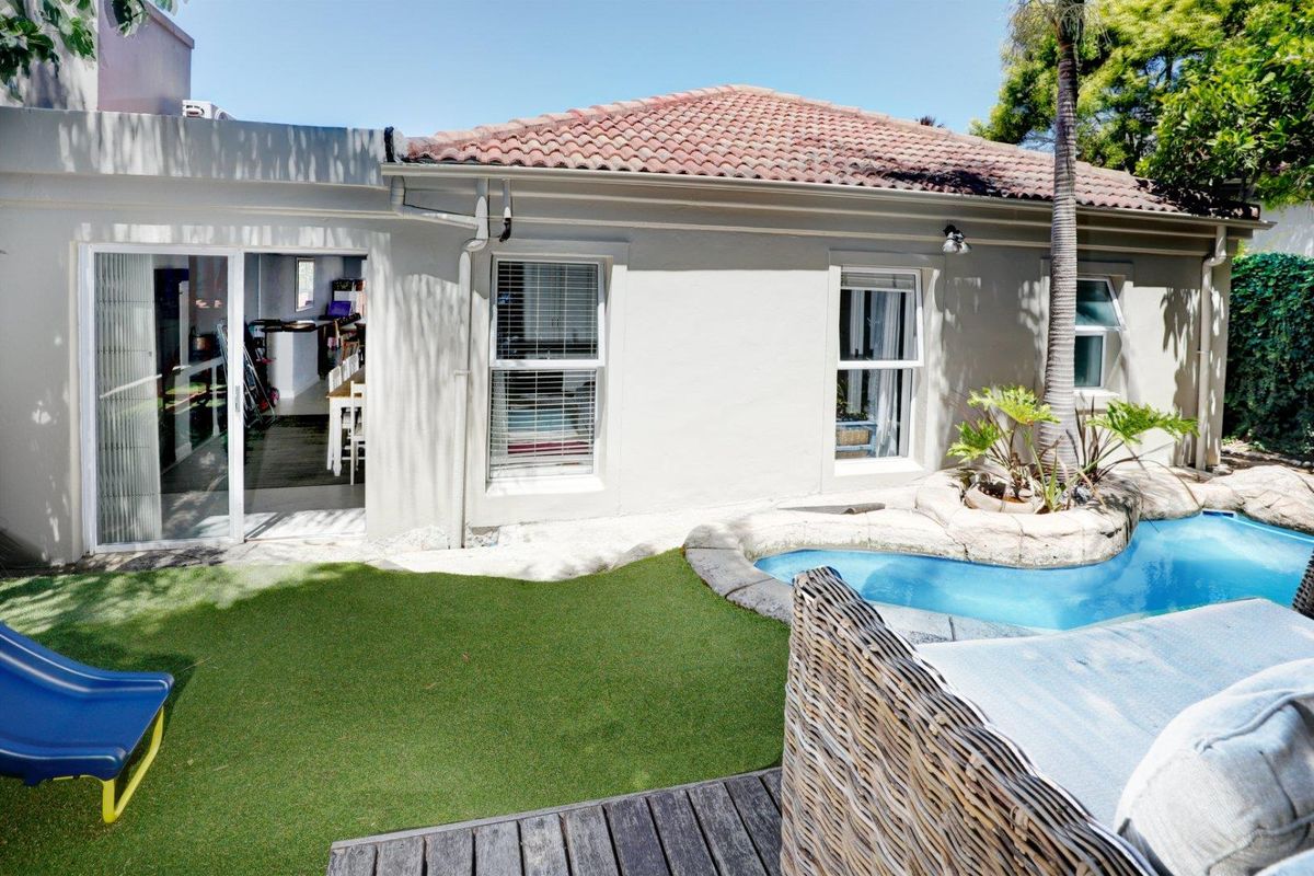 Rear view of the townhouse featuring a small swimming pool, artificial lawn, and sliding door access to the interior living space.
